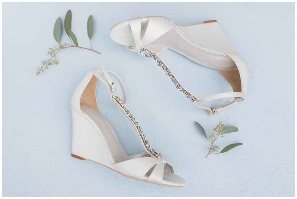 bride's white shoes in a flatlay with greenery