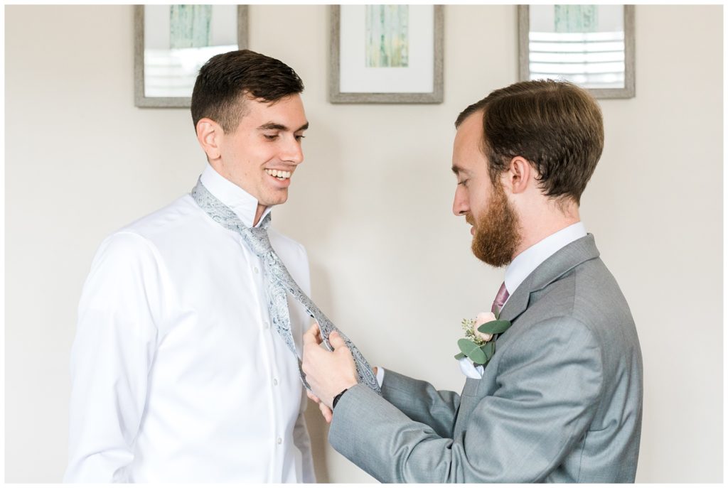 groom and best man getting ready and putting on a tie 