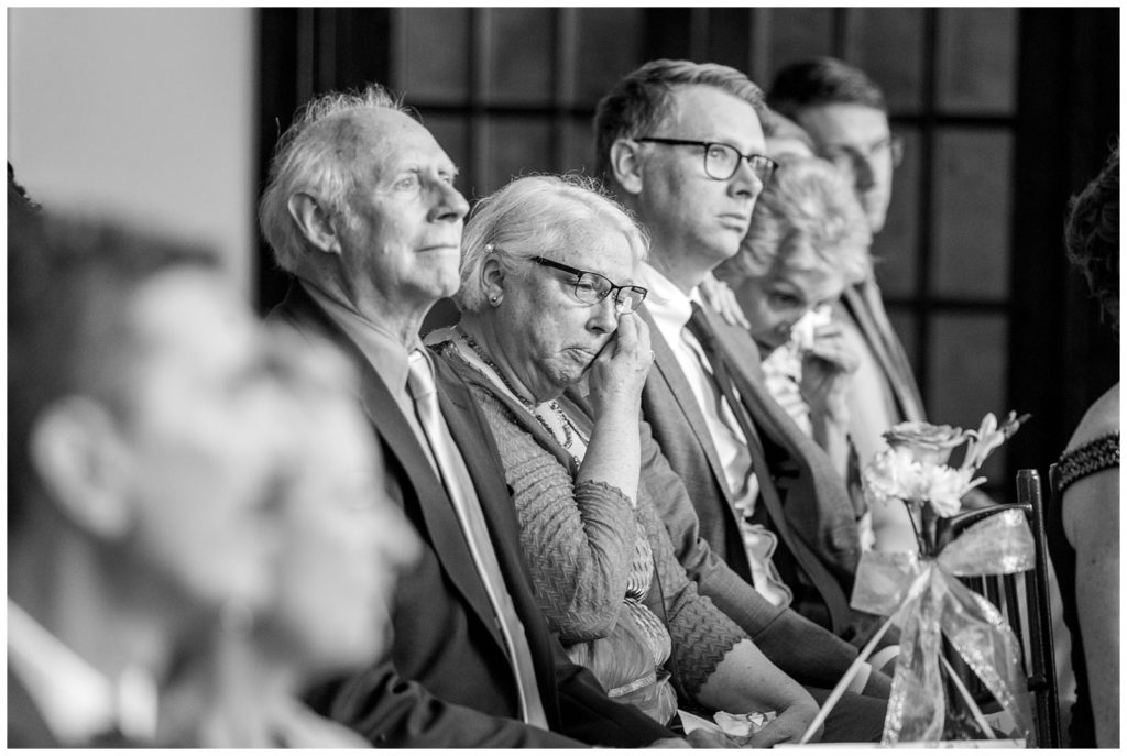 emotional black and white photograph of wedding guest tearing up during the ceremony 